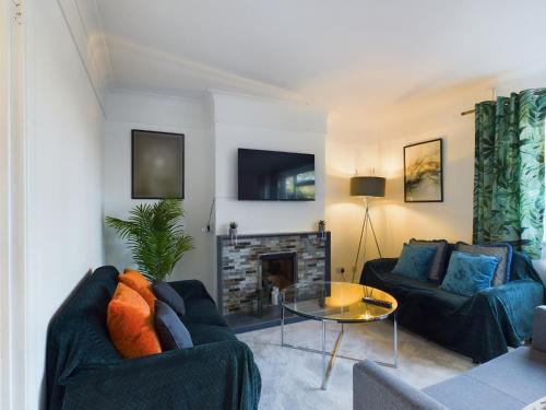 a living room with two blue couches and a fireplace at 3 bed beautiful home which sleeps up to 6 in Tilehurst