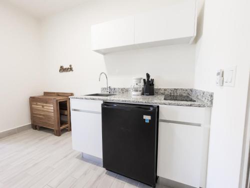 a kitchen with a black refrigerator and white cabinets at Ventanas del Mar by Playa Caracol 3 Habitaciones in Punta Chame