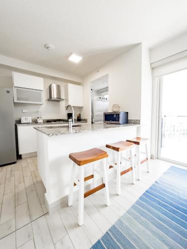 a white kitchen with a counter and two stools at Ventanas del Mar by Playa Caracol 3 Habitaciones in Punta Chame