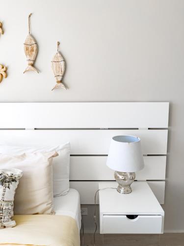 a bed with a white headboard and a lamp on a night stand at Ventanas del Mar by Playa Caracol 3 Habitaciones in Punta Chame