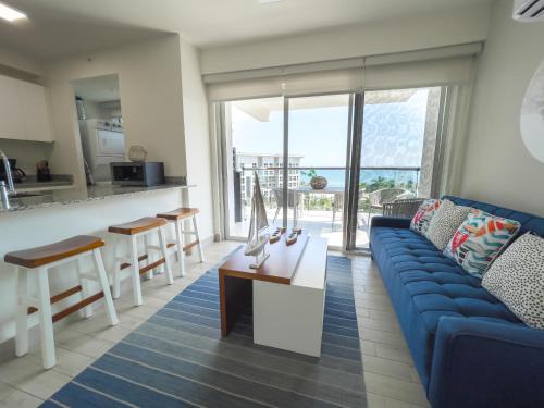 a living room with a blue couch and a kitchen at Ventanas del Mar by Playa Caracol 3 Habitaciones in Punta Chame