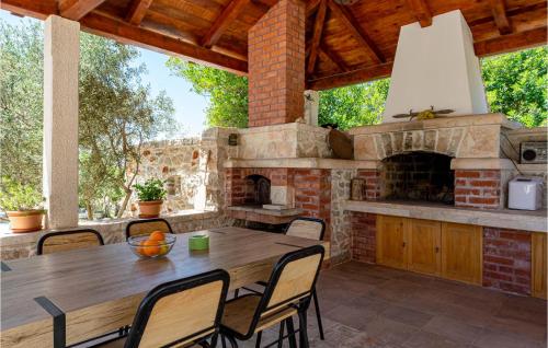 an outdoor patio with a wooden table and a fireplace at 2 Bedroom Lovely Home In Blato in Blato