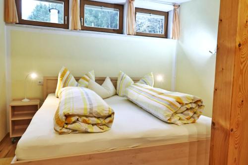 a bed with pillows on it in a room with windows at Appartements-Klaus in Neustift im Stubaital