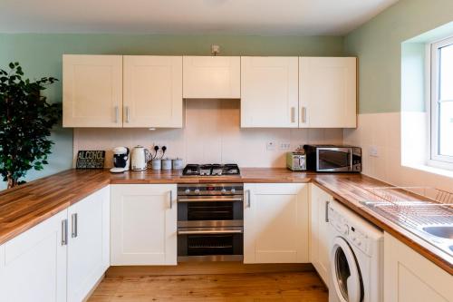a kitchen with white cabinets and a stove top oven at Jungle House in Chichester