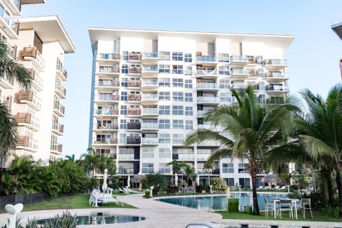 an apartment building with a pool and palm trees at Ventanas del Mar by Playa Caracol 3 Habitaciones in Punta Chame