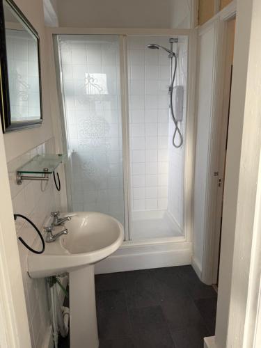a white bathroom with a shower and a sink at Sunset Hideaway, Bridlington in Bridlington