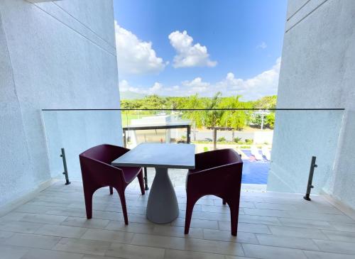 a table and chairs on a balcony with a view of a pool at Sanctuary by Playa Caracol Frente al Mar in Punta Chame