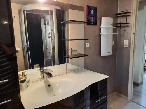 une salle de bain avec un lavabo et un grand miroir dans l'établissement 70 M2 Maison Moderne 3 étoiles TARIFS 2026, à Saint Pierre La Mer