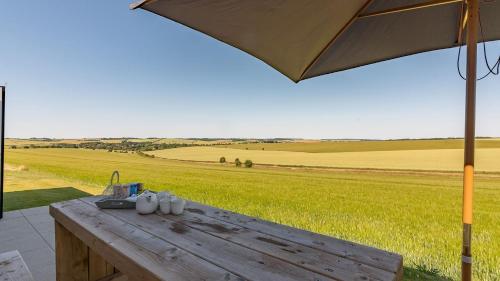 a wooden table with mugs on it with an umbrella at Downs in Blewbury