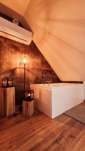 - une salle de bains mansardée pourvue d'une baignoire blanche dans l'établissement Loft de charme pour amoureux, à Grendelbruch
