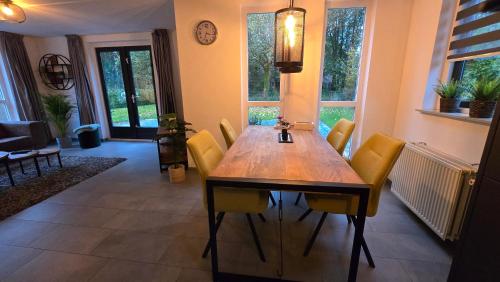 a dining room with a wooden table and yellow chairs at Vakantiewoning Maas en Waal in Ewijk