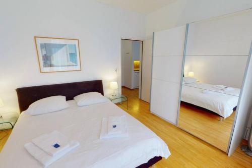 a bedroom with a large white bed and a mirror at Nice 1BR apartment near lake - FB6 in Zürich