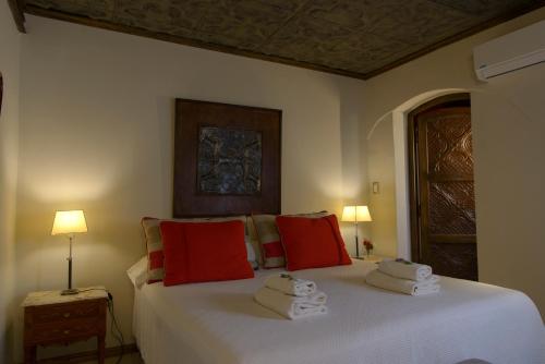 a bedroom with a large white bed with red pillows at Posada Verde Oliva in Maipú