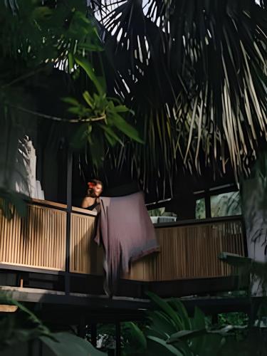 a woman sitting on a bench in a room with trees at Tumbo Resort in Cabo Matapalo