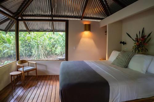 a bedroom with a large bed and a large window at Tumbo de las Olas in Cabo Matapalo