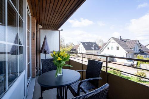 a balcony with a table and chairs and a vase of flowers at _DKK9_ Ferienwohnung Moewennest in Niendorf