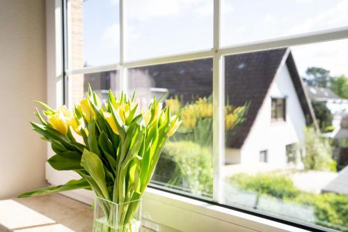 a vase of yellow flowers sitting on a window sill at _DKK9_ Ferienwohnung Moewennest in Niendorf