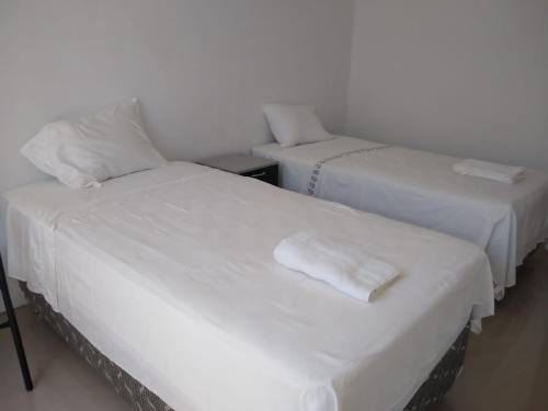 two beds with white sheets in a room at LA COLINA Casa-Hospedaje in Máncora