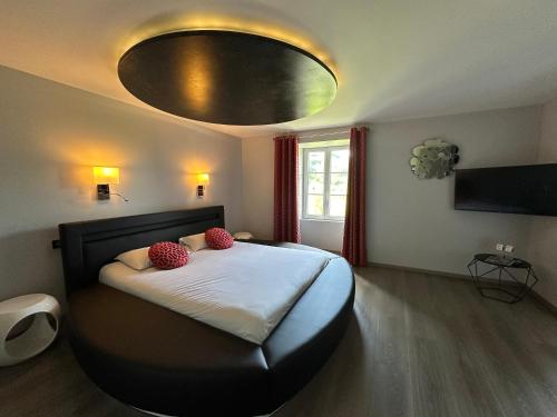 a bedroom with a bed with two red pillows on it at Château de la Falque, The Originals Relais in Saint-Geniez-dʼOlt