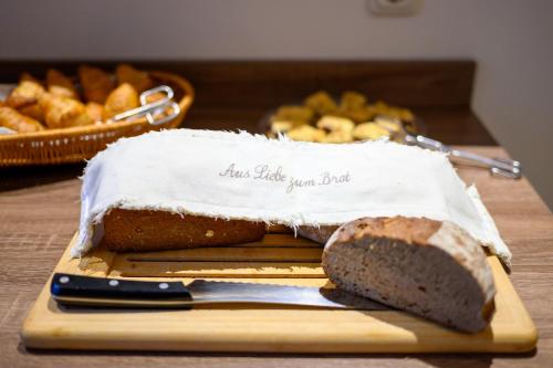 a loaf of bread sitting on a cutting board with a knife at Hotel Zur Seemöwe in Kirchdorf