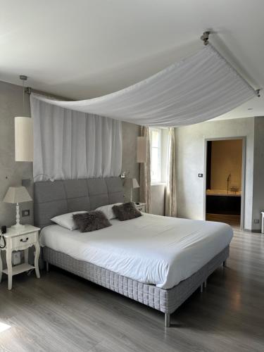 a bedroom with a large white bed with a canopy at Château de la Falque, The Originals Relais in Saint-Geniez-dʼOlt