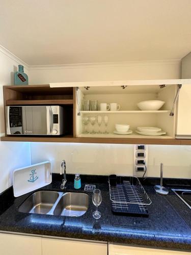 a kitchen counter with a sink and a microwave at Green Park hermoso apartamento vista al lago in Punta del Este