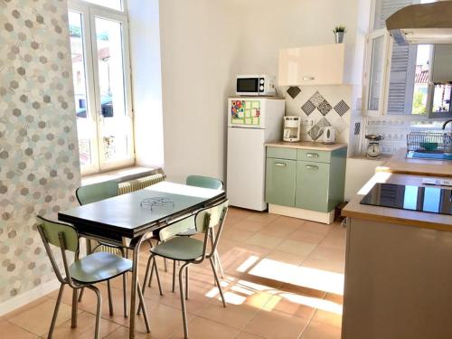 une cuisine avec une table, des chaises et un réfrigérateur dans l'établissement Grand T2 lumineux rénové Lamalou centre, à Lamalou-les-Bains
