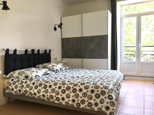 une chambre avec un grand lit avec une grande fenêtre dans l'établissement Grand T2 lumineux rénové Lamalou centre, à Lamalou-les-Bains