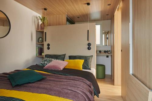 a bedroom with a large bed with colorful pillows at Camping Club l'Air Marin in Vias