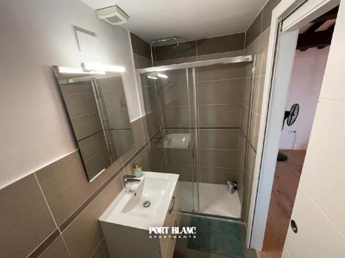 a bathroom with a sink and a shower with a mirror at PortBlanc Apartments - 4 in Arenys de Mar