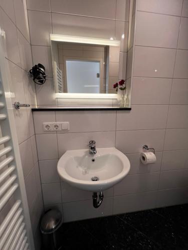 a white bathroom with a sink and a mirror at Atelier Reinhart in Rauhenebrach