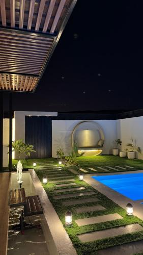 a house with a pool and a yard with lights at sandhut77 in Al Raka