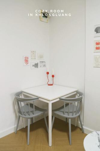 a white table with two chairs and a candle on it at Cozy room in Khlongluang - Self Check-in in Khlong Luang