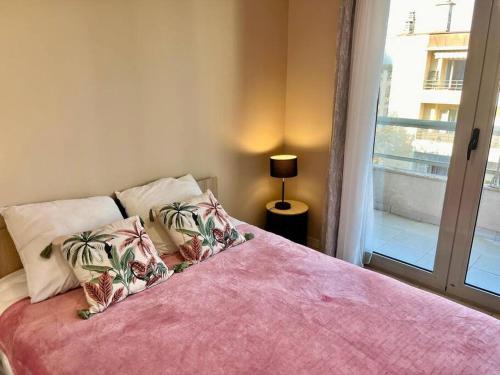 - une chambre avec un lit avec des draps roses et une fenêtre dans l'établissement Eden Blue YourHostHelper, à Antibes