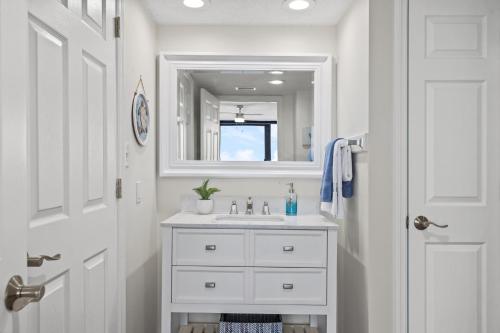 a white bathroom with a sink and a mirror at Sandpiper Beacon Beach Resort in Panama City Beach