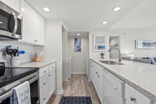 a kitchen with white cabinets and a sink at Sandpiper Beacon Beach Resort in Panama City Beach