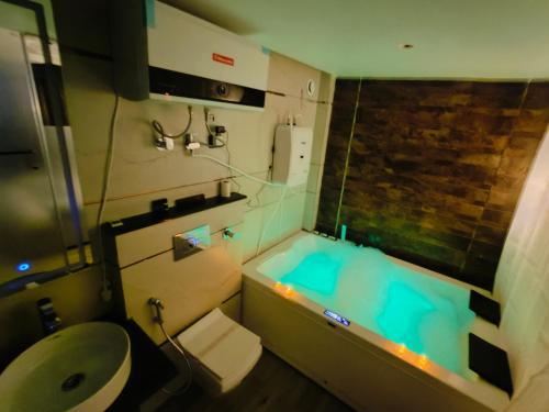 a bathroom with a blue tub and a toilet at The Vacation Villa in Agra