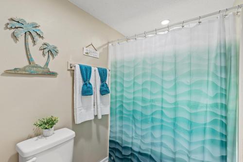 a bathroom with a blue shower curtain with a palm tree at Sandpiper Beacon Beach Resort in Panama City Beach