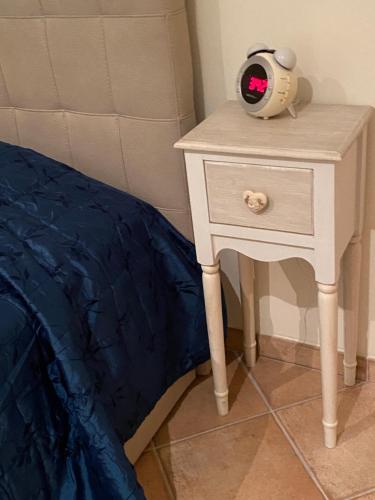 a nightstand with a alarm clock on it next to a bed at Rhome country lodge in La Massimina-Casal Lumbroso