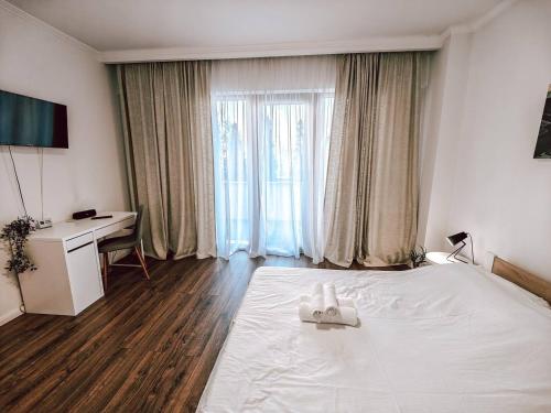 a bedroom with a white bed and a desk at Luminia Apartment in Cluj-Napoca