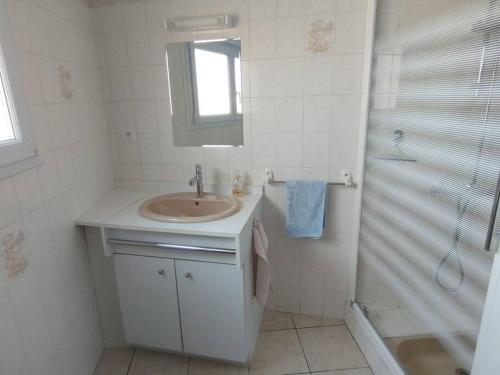 une salle de bain blanche avec un lavabo et une douche dans l'établissement Gîte ARDELAY et son jardin, 10 min du Grand Parc, aux Herbiers