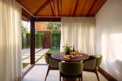 a dining room with a table with a bottle of wine at Zendaya Resort Beach Sport & Spa in Búzios