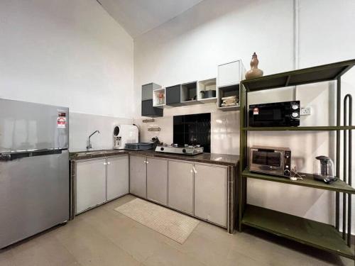 a large kitchen with stainless steel cabinets and appliances at Merpati Dusun Retreat in Kepala Batas