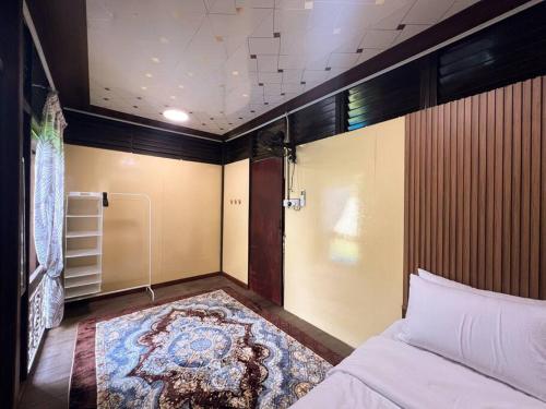 a bedroom with a bed and a rug on the floor at Merpati Dusun Retreat in Kepala Batas