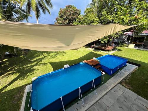 two blue tables and a hammock in a yard at Merpati Dusun Retreat in Kepala Batas