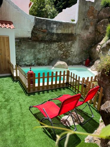 a pair of red chairs in front of a pool at Bloom Cottage I - Sintra montain in Sintra