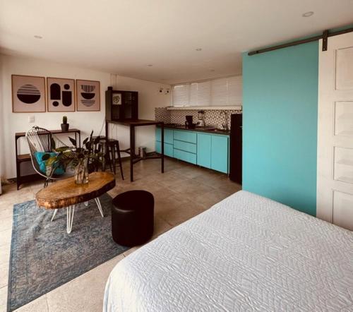 a bedroom with a bed and a table and a kitchen at Moonshine Boutique Hostal in Cali