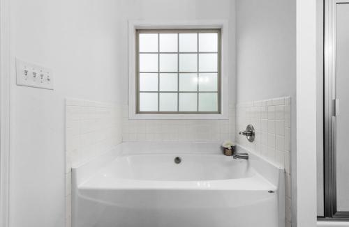 a white bathroom with a tub and a window at The Gate 4 Getaway! in Oak Grove