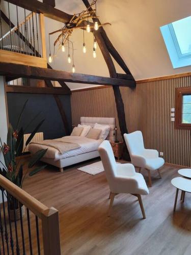 - un salon avec un lit et deux chaises et un escalier dans l'établissement Le Petit Paradis, à Bouafles
