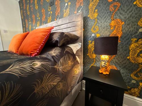 a bed with orange pillows and a lamp on a table at Bounty Town House Cumbria in Whitehaven